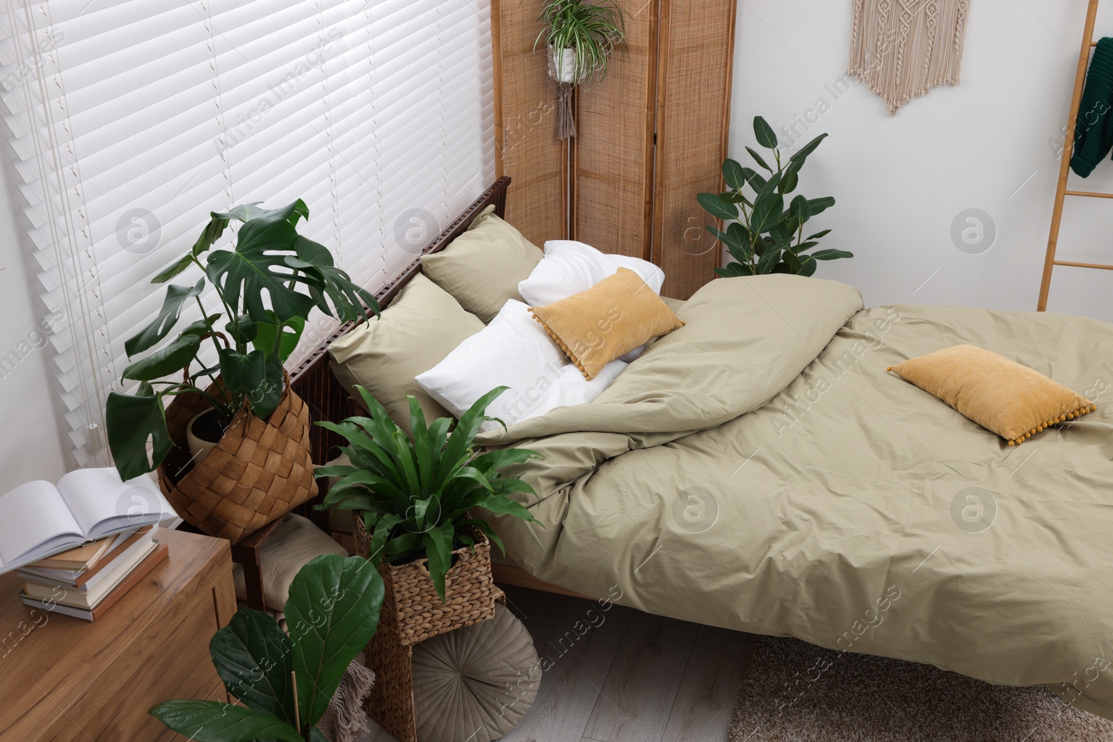 Photo of Stylish bedroom with comfortable bed and beautiful green houseplants, above view. Interior design