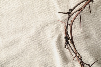 Photo of Crown of thorns on white fabric, top view with space for text. Easter attribute