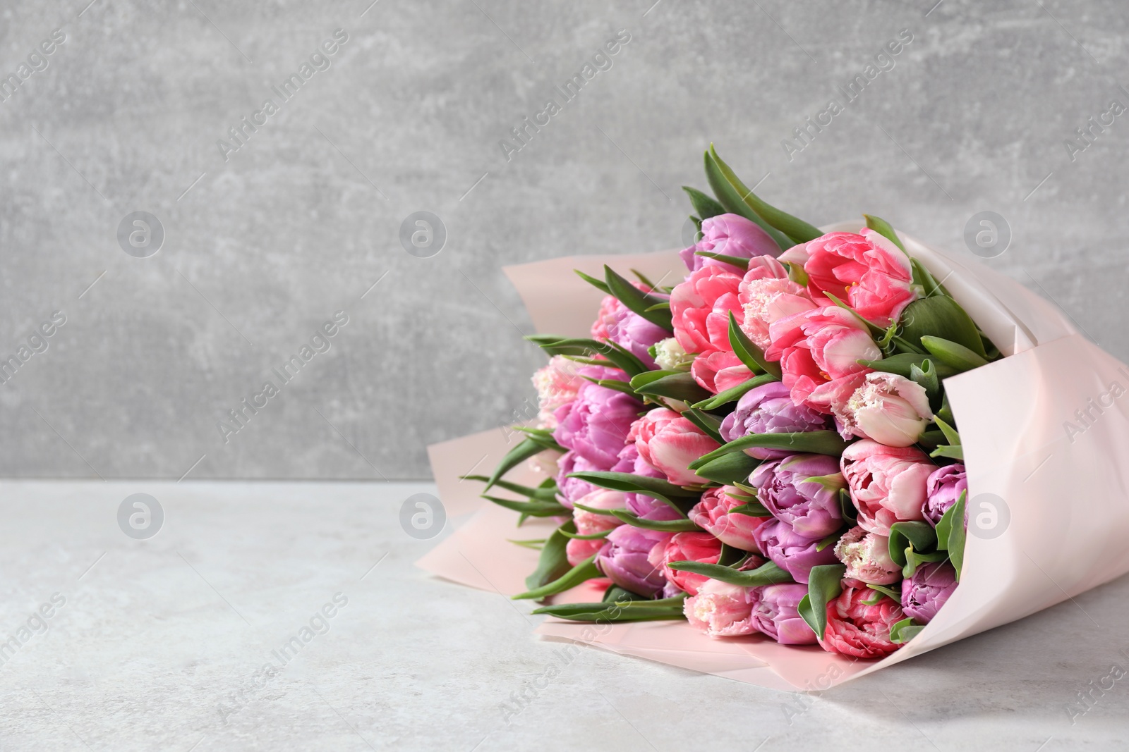 Photo of Bouquet of beautiful tulips on white table. Space for text