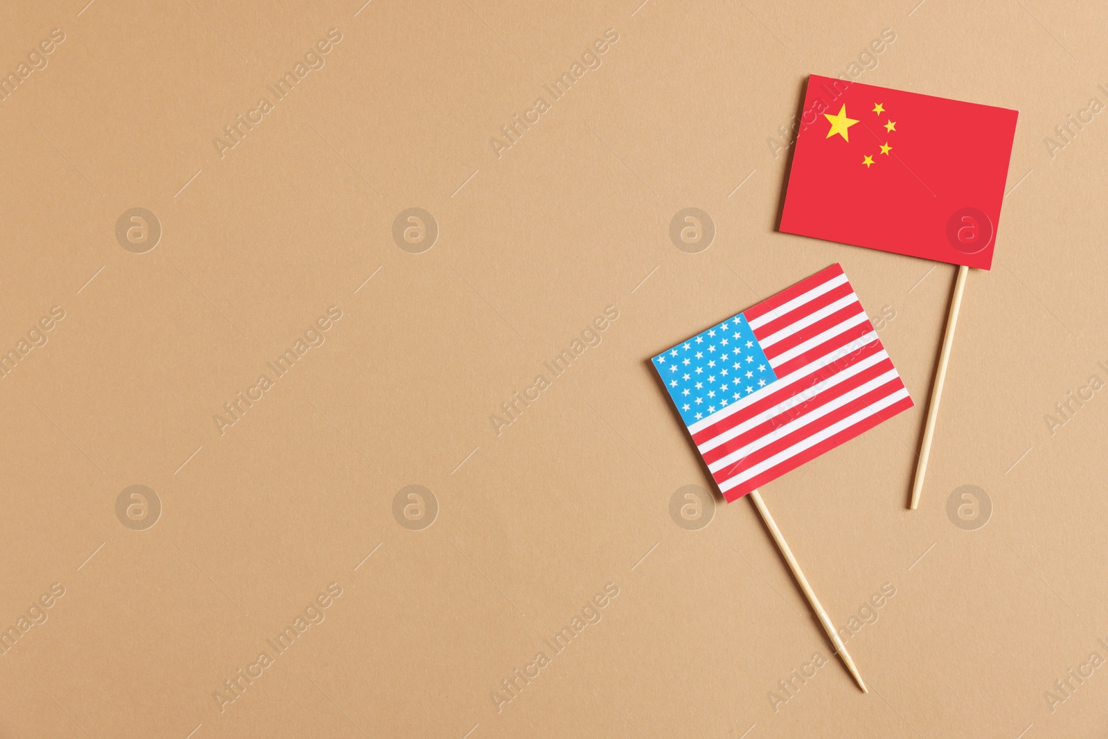 Photo of American and Chinese flags in beige background, top view with space for text. Trade war