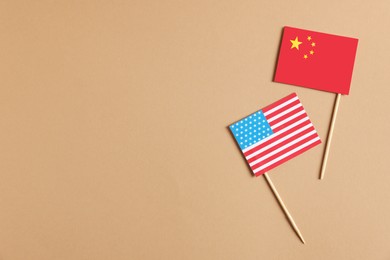 Photo of American and Chinese flags in beige background, top view with space for text. Trade war