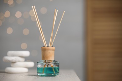 Photo of Aromatic reed air freshener and pebbles on wooden table. Space for text