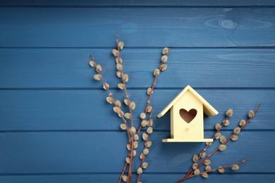 Photo of Beautiful bird house and pussy willow branches on blue wooden table, flat lay. Space for text