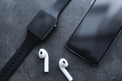 Photo of Stylish smart watch, phone and earphones on grey table, above view