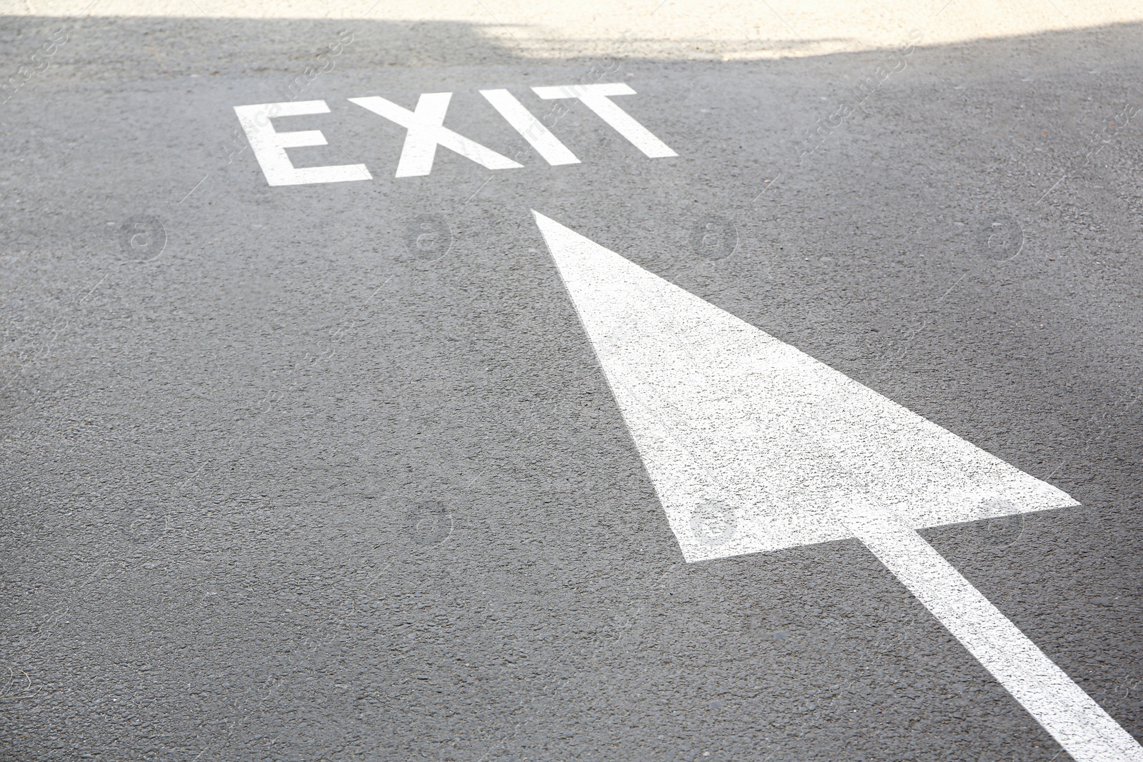 Photo of White painted arrow and exit marking on road outdoors