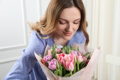 Young woman with bouquet of beautiful tulips indoors