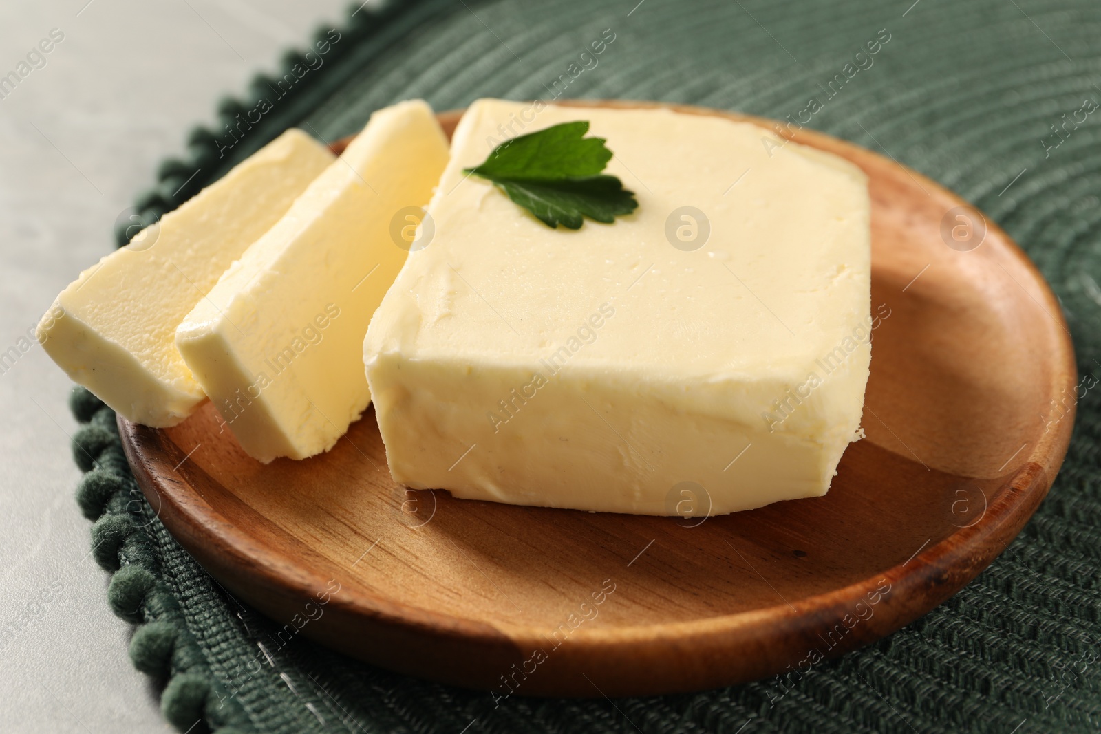 Photo of Cut tasty butter with parsley on grey table, closeup