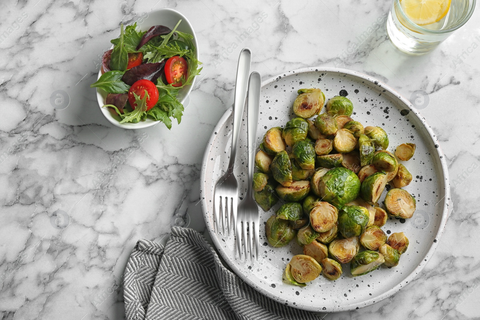 Photo of Delicious roasted brussels sprouts on white marble table, flat lay