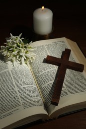 Photo of Church candle, Bible, cross and flowers on wooden table