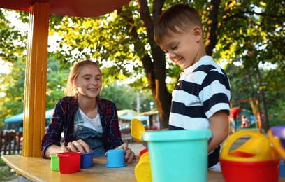 Teen nanny and cute little boy playing outdoors