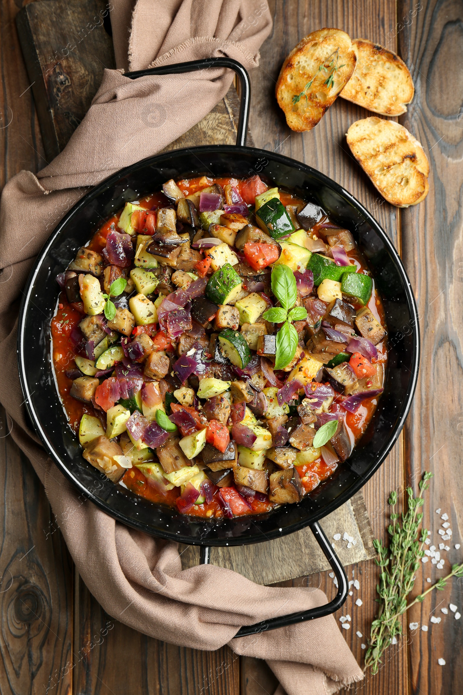 Photo of Delicious ratatouille in baking dish served on wooden table, flat lay