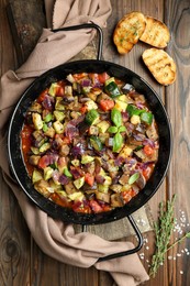 Delicious ratatouille in baking dish served on wooden table, flat lay