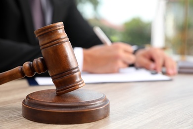 Judge with gavel at wooden table indoors, closeup. Criminal law