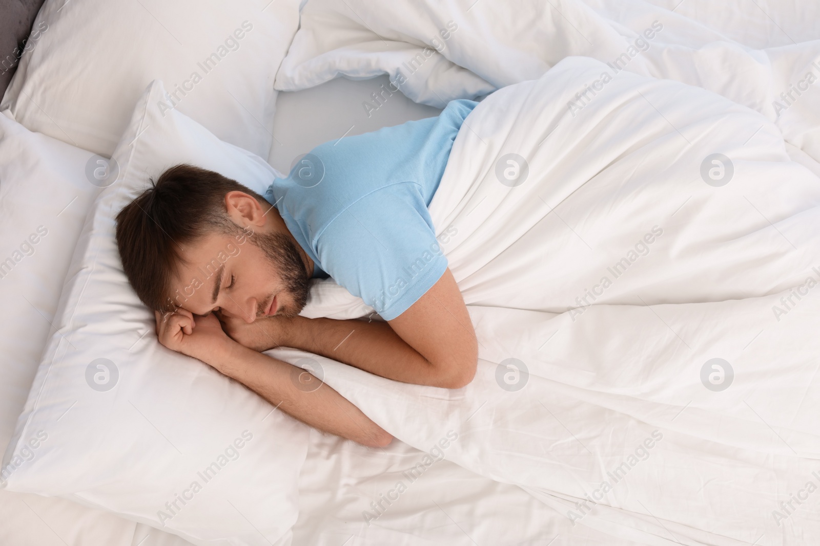 Photo of Young handsome man sleeping in bed at home, above view. Early morning