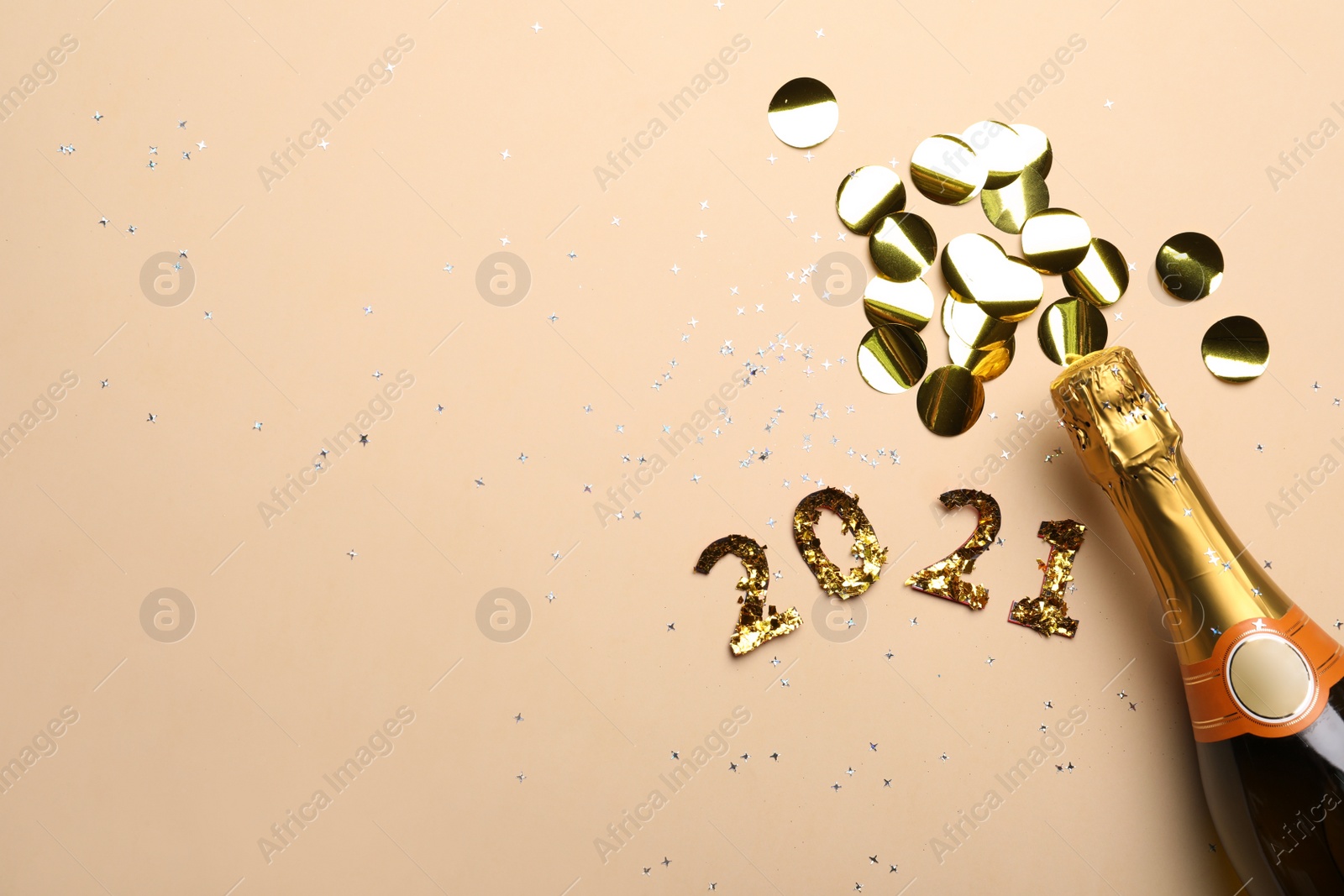 Photo of Year number 2021, champagne bottle and shiny confetti on beige background, flat lay. Space for text