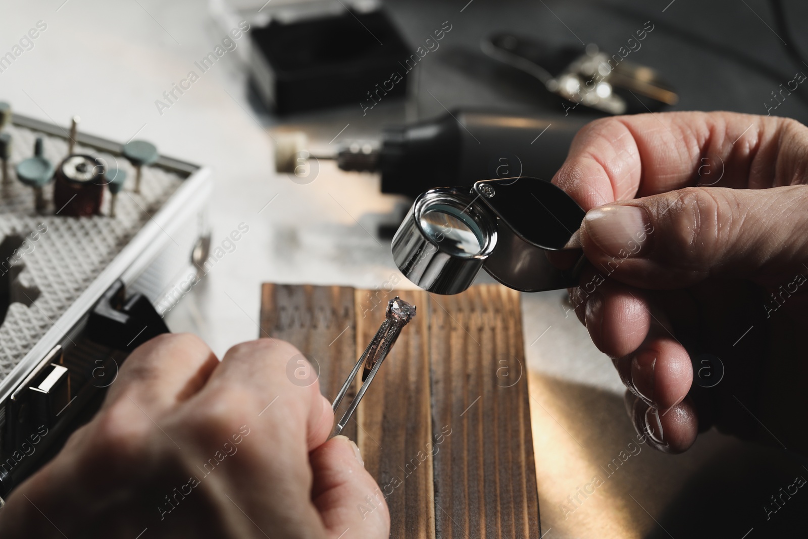 Photo of Professional jeweler working with ring at table, closeup