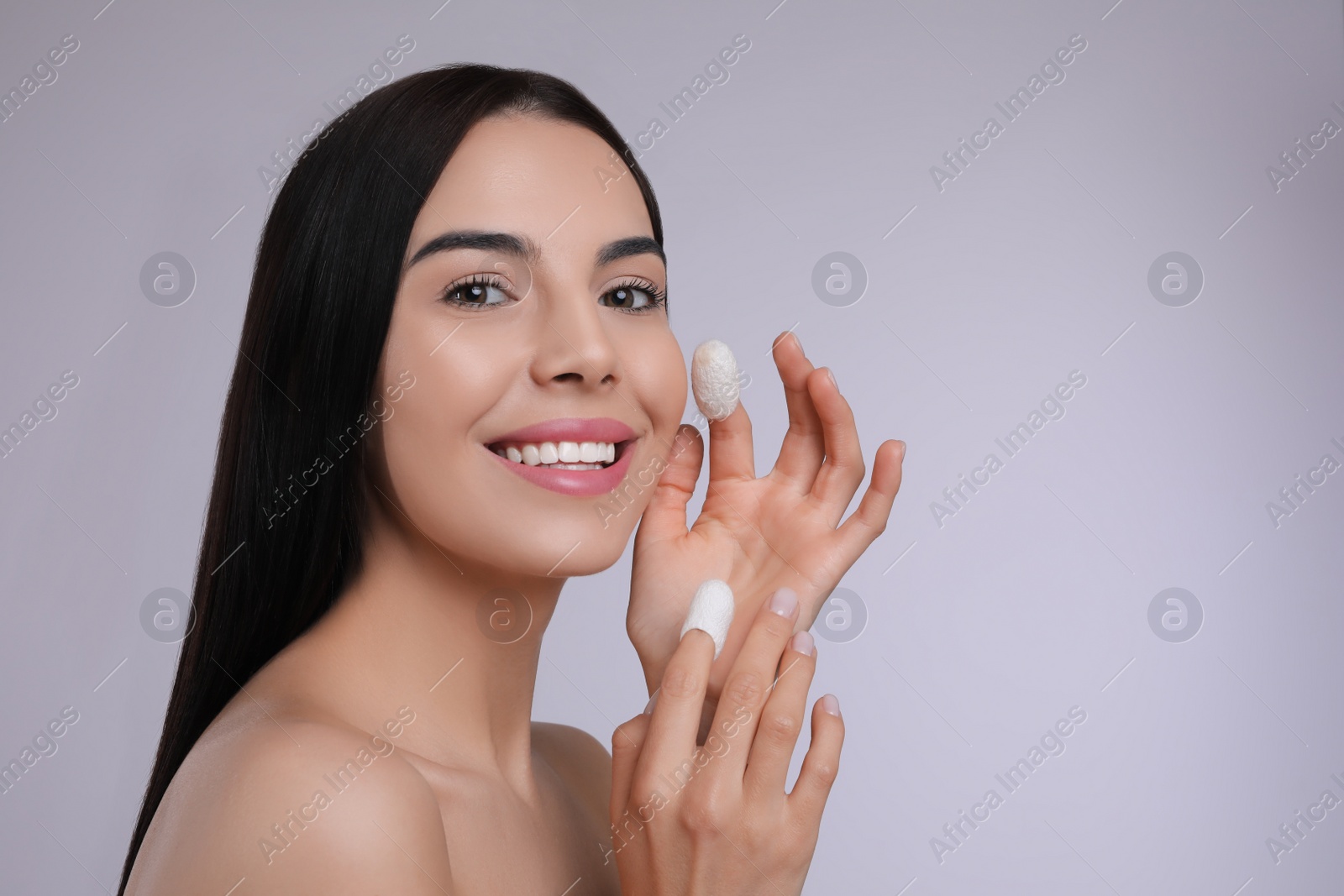 Photo of Woman using silkworm cocoons in skin care routine on light grey background. Space for text