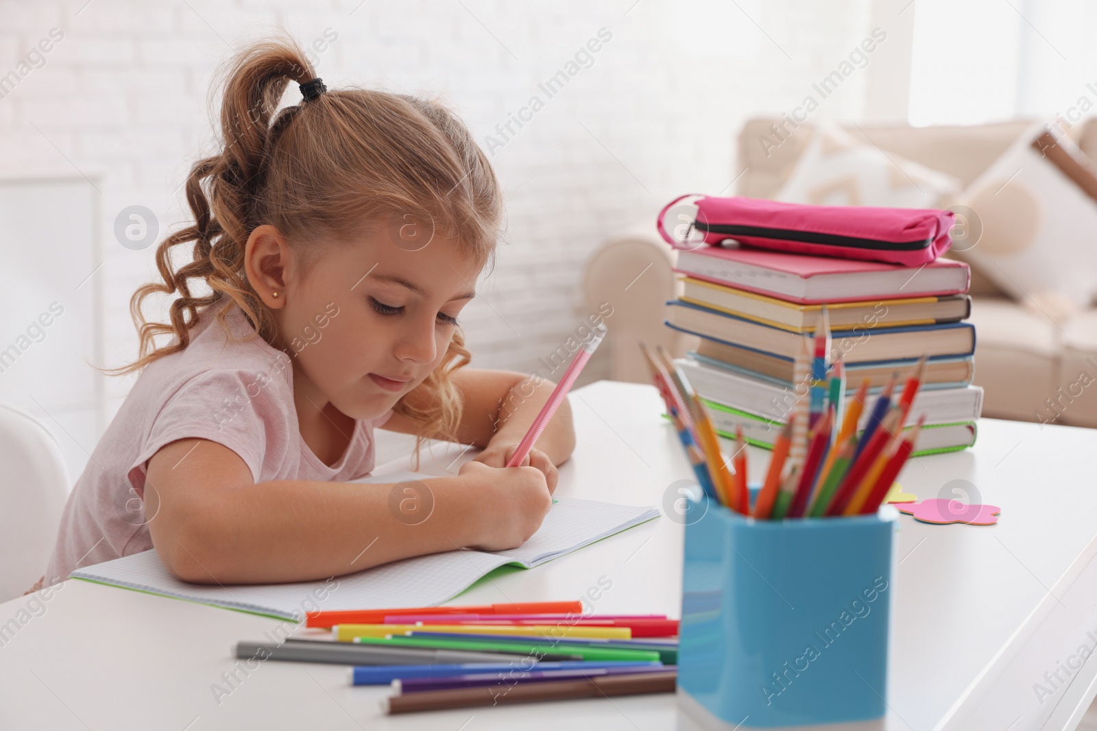 Photo of Cute little girl doing homework at table