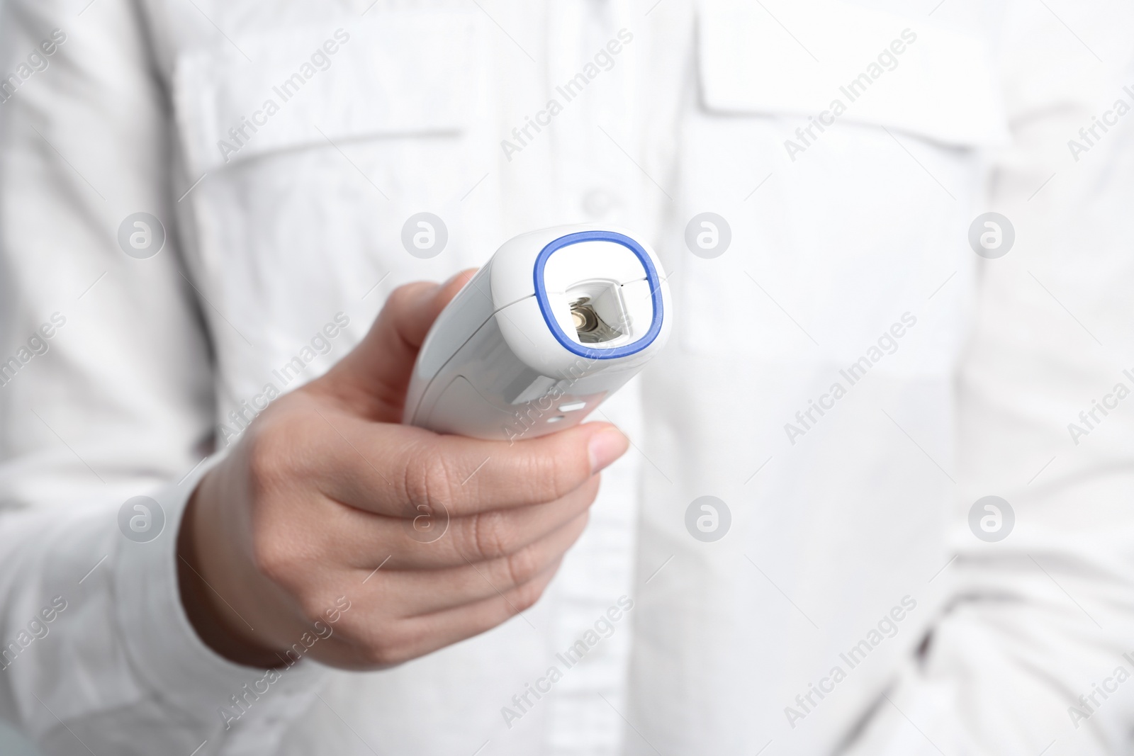 Photo of Woman holding non contact infrared thermometer, closeup