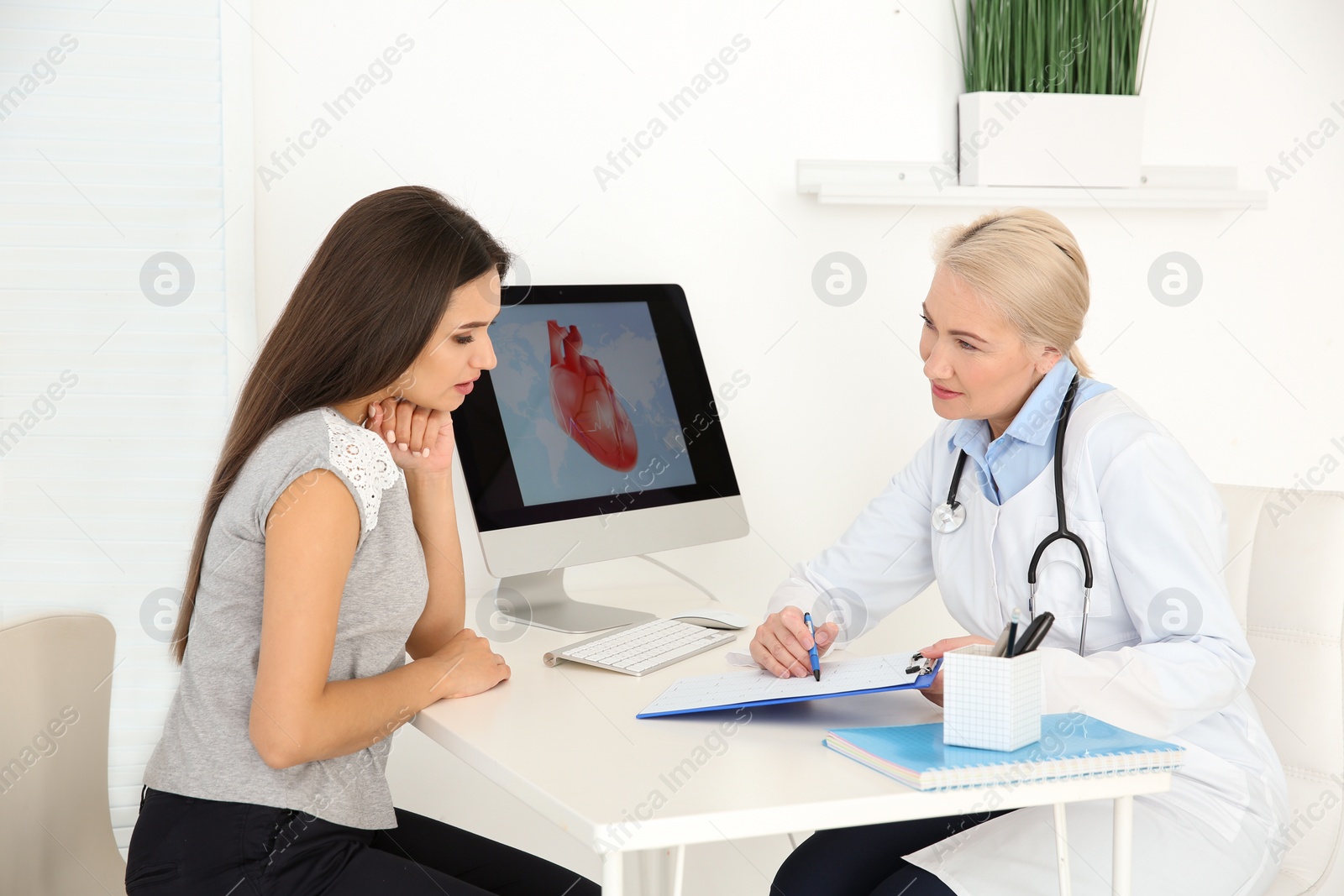 Photo of Female doctor working with patient in clinic. Cardiology consultation
