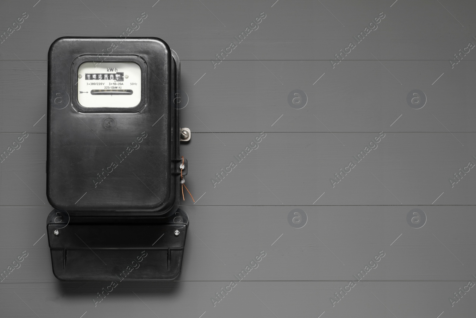 Photo of Electricity meter on grey wooden wall, space for text