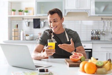 Portrait of food blogger with laptop in kitchen. Online broadcast