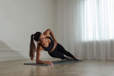 Photo of Young woman doing side plank exercise at home