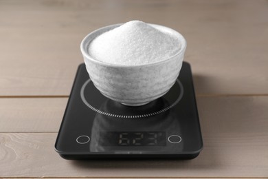 Photo of Electronic scales with sugar on light wooden table