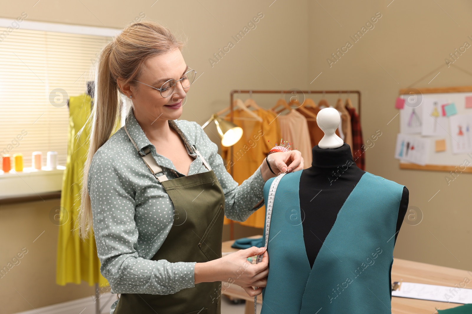 Photo of Dressmaker with measuring tape working in atelier