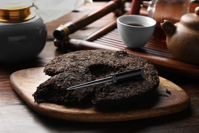 Photo of Broken disc shaped pu-erh tea and knife on wooden table