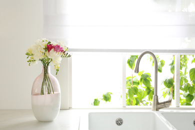 Beautiful bouquet of freesia flowers on countertop in kitchen