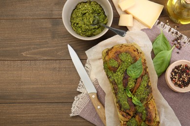 Photo of Freshly baked pesto bread with ingredients on wooden table, flat lay. Space for text