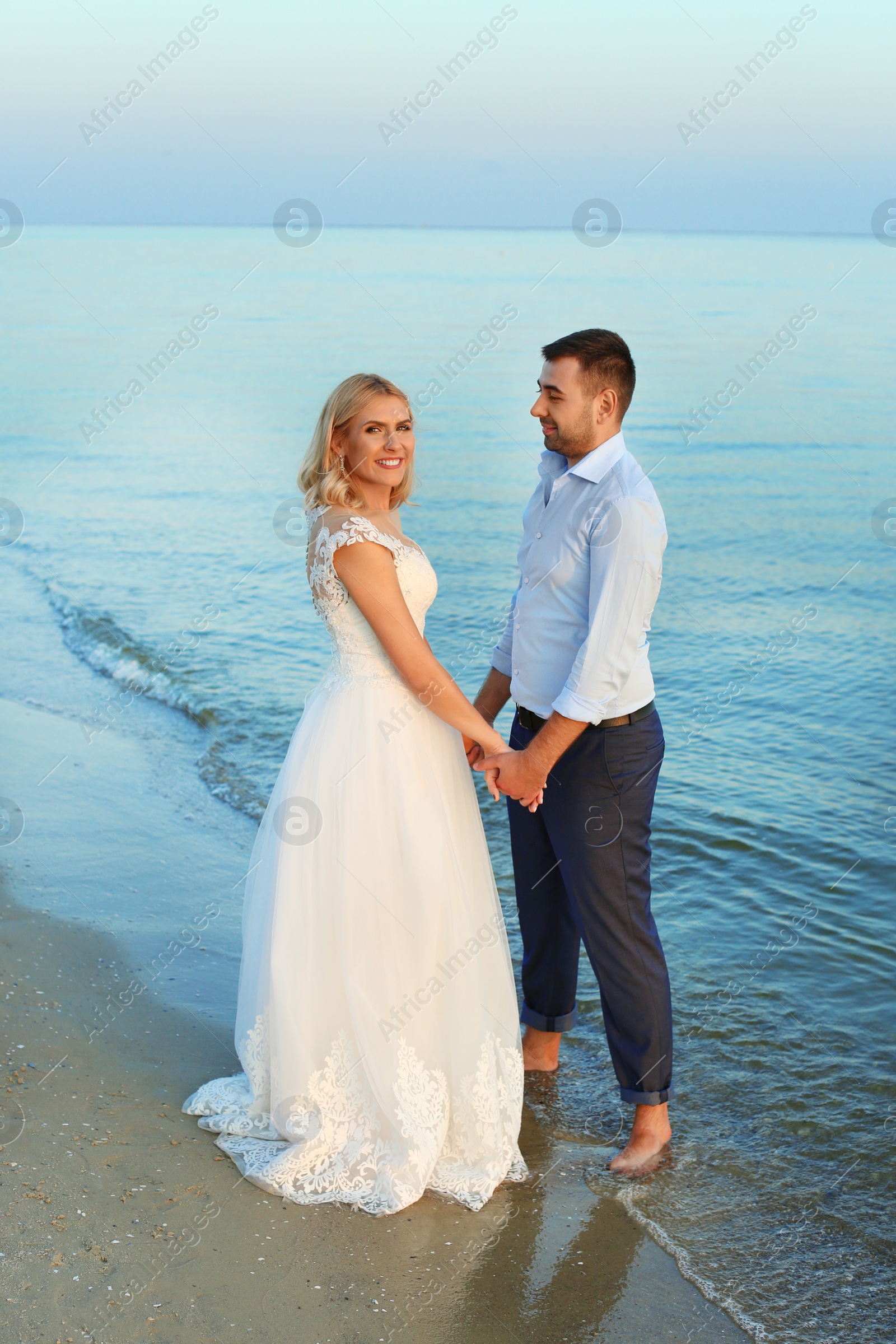 Photo of Wedding couple. Bride and groom holding hands on beach