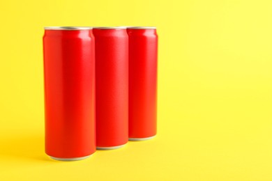 Energy drinks in red cans on yellow background, space for text