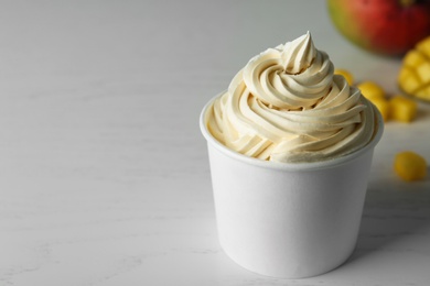 Cup with tasty frozen yogurt on light wooden table. Space for text