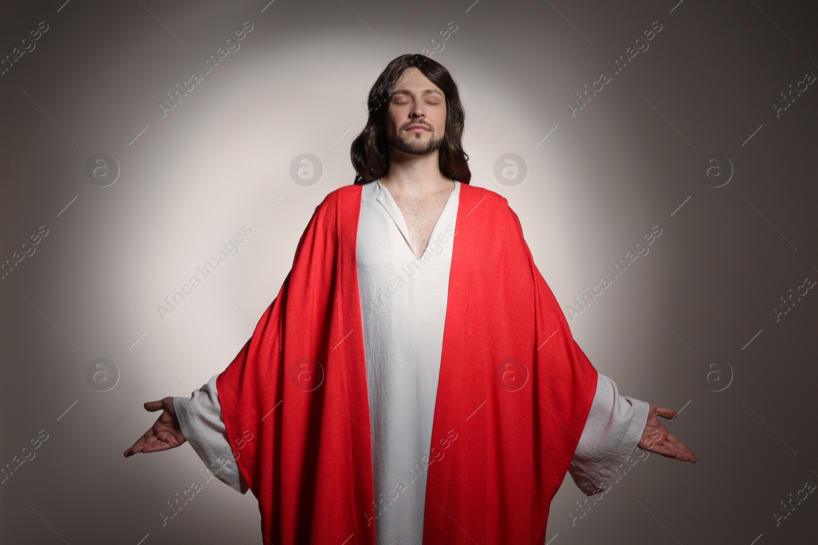 Photo of Jesus Christ with outstretched arms on beige background