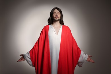 Photo of Jesus Christ with outstretched arms on beige background