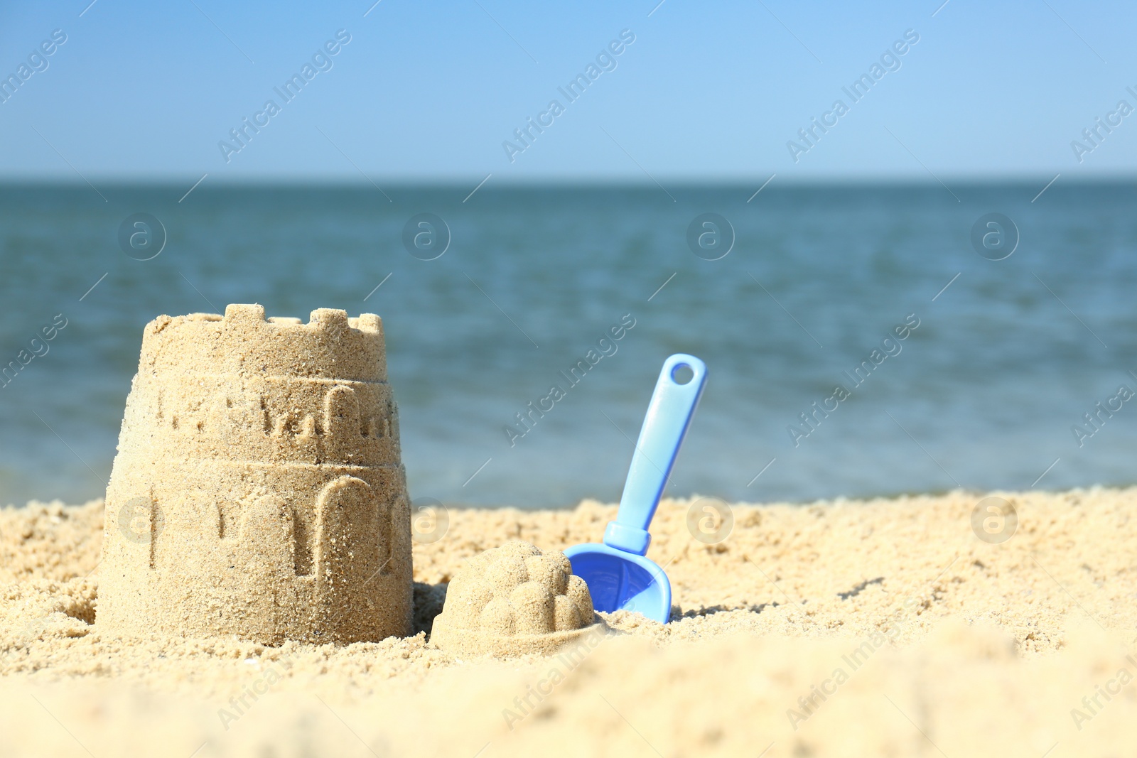 Photo of Beautiful view of beach with sand figure and shovel near sea. Space for text