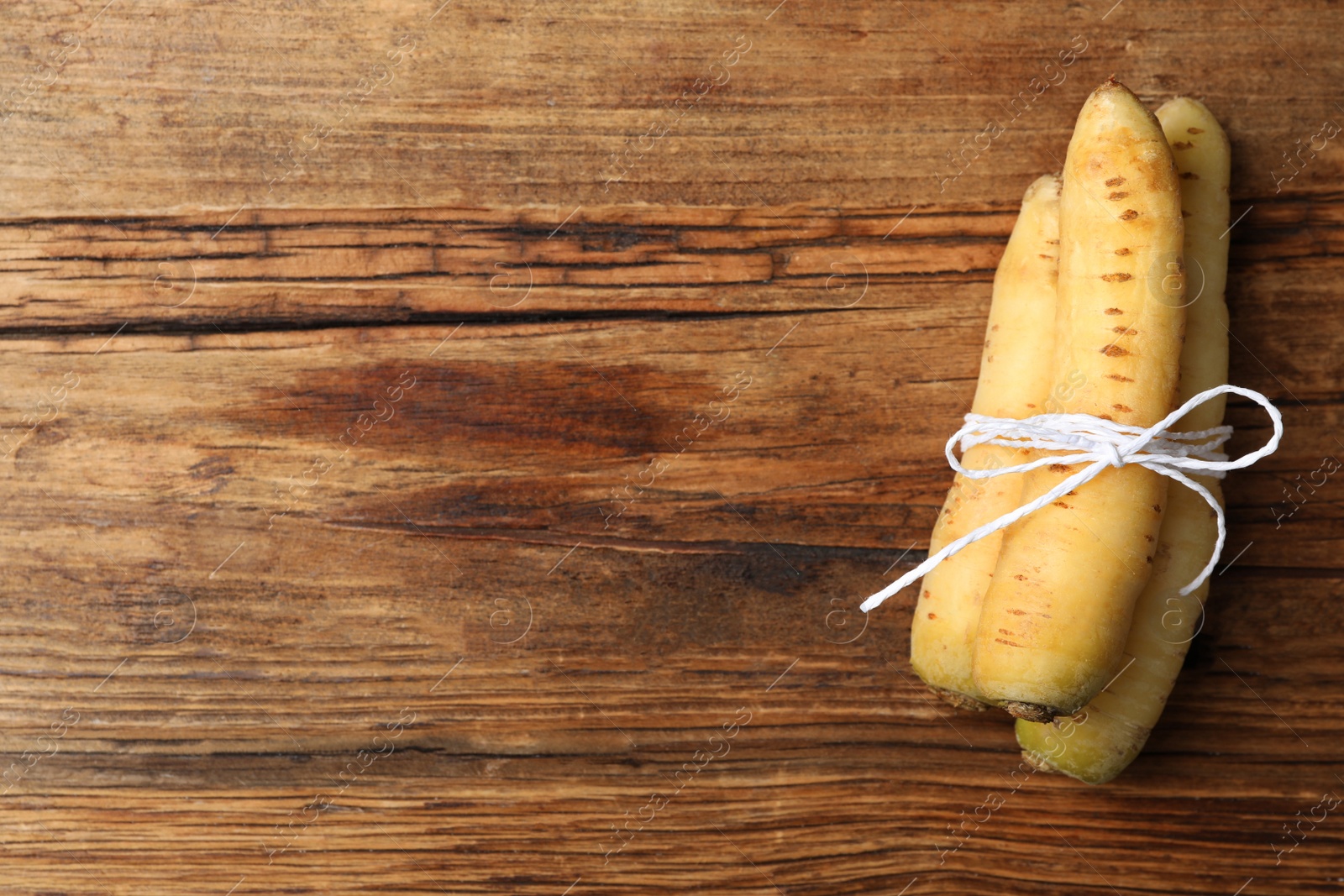 Photo of Raw white carrots on wooden table, top view. Space for text