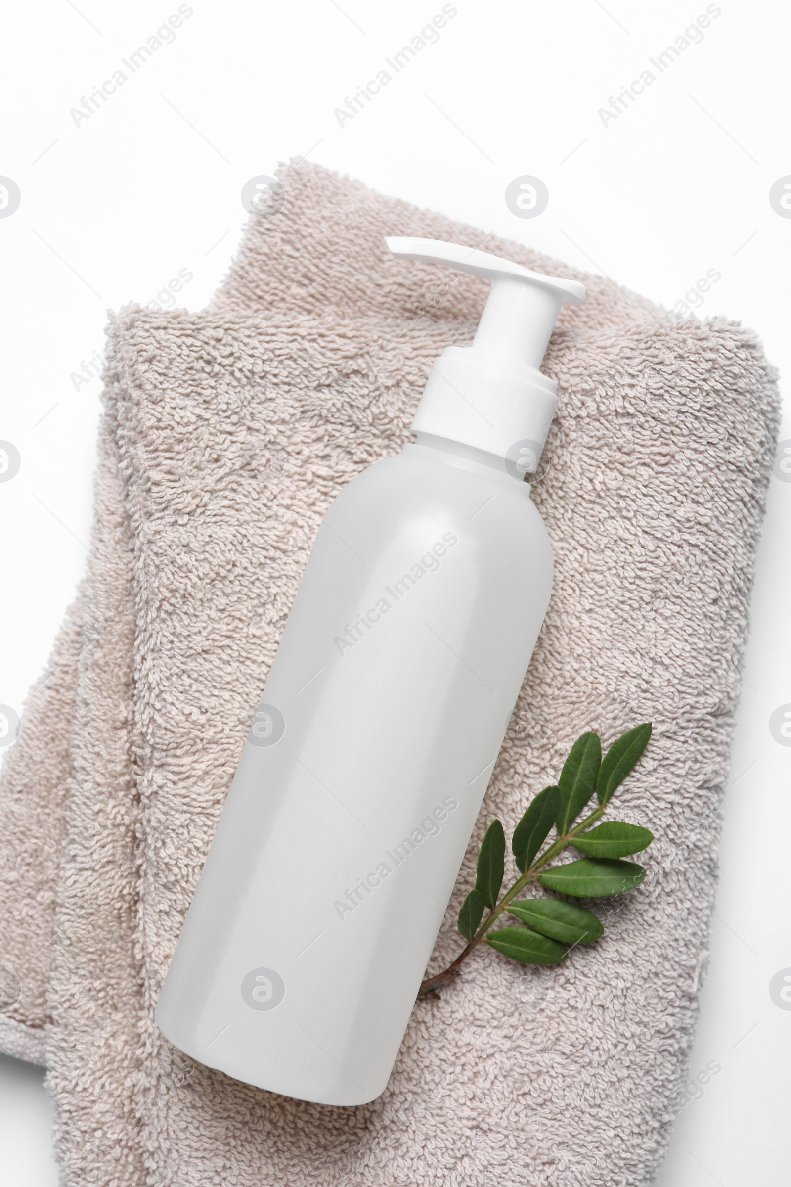 Photo of Bottle of cosmetic product, green leaves and soft towel on white background, top view