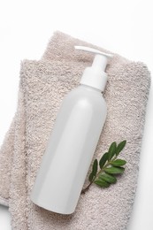 Bottle of cosmetic product, green leaves and soft towel on white background, top view