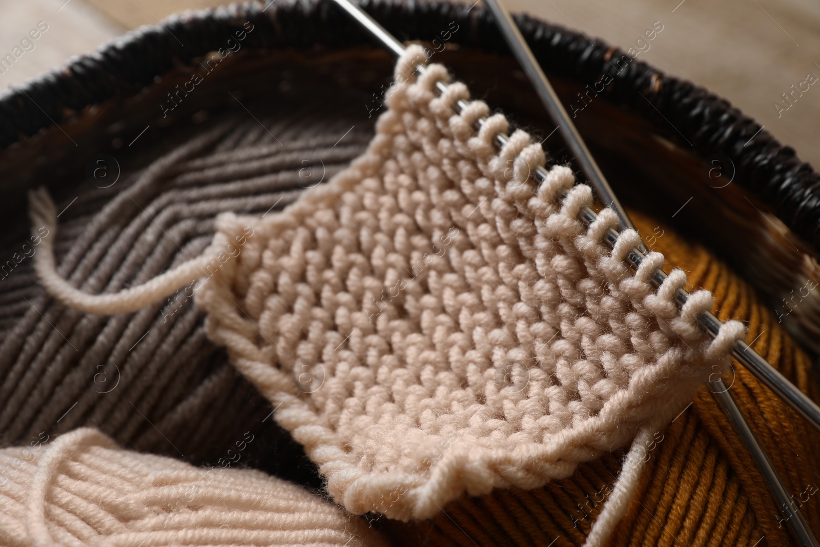 Photo of Soft colorful yarns, knitting and metal needles on wooden table, closeup