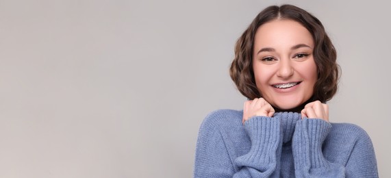 Image of Smiling woman with braces on grey background. Banner design with space for text