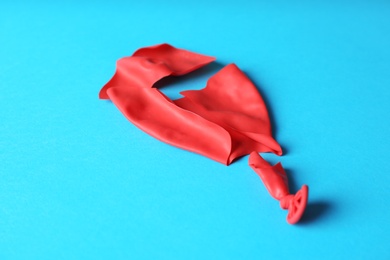 Popped red latex balloon on color background