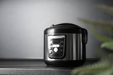 Photo of Modern multi cooker on table near black wall, space for text