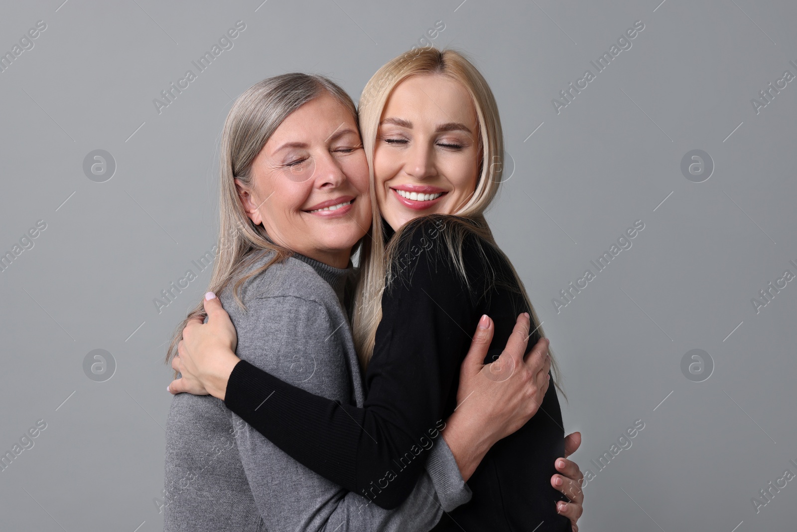 Photo of Family portrait of young woman and her mother on grey background