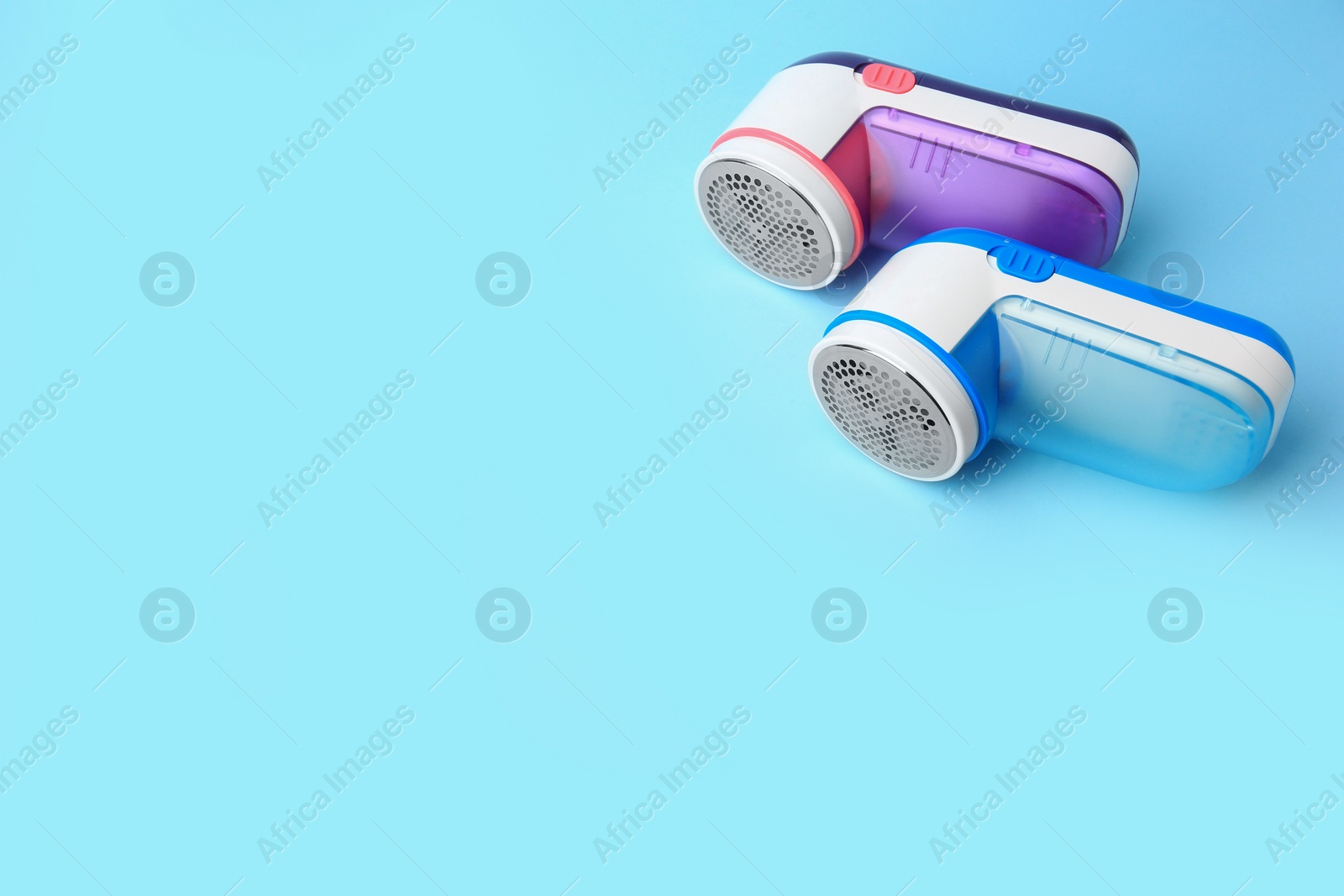 Photo of Modern fabric shavers on light blue background, above view. Space for text