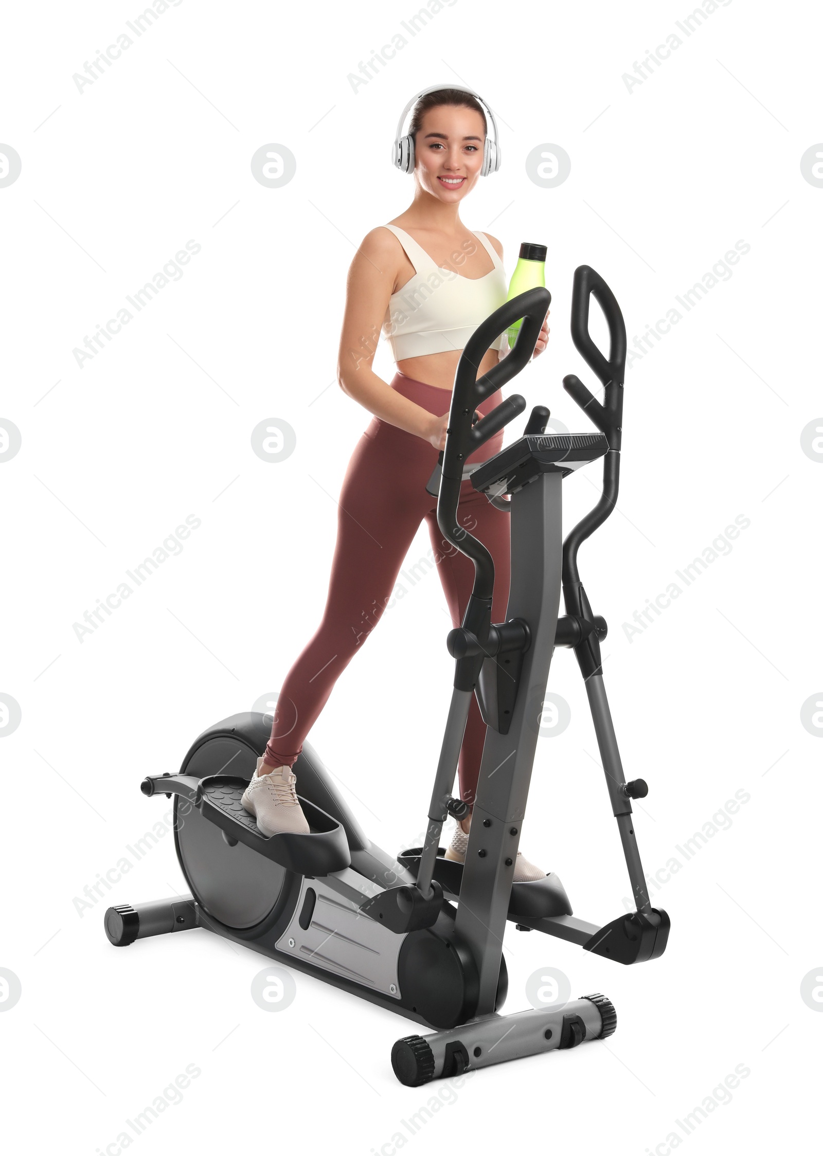 Photo of Woman with bottle using modern elliptical machine on white background