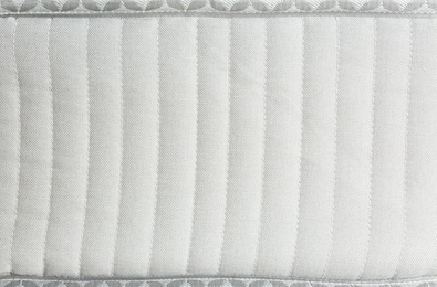 Photo of Modern comfortable orthopedic mattress as background, closeup