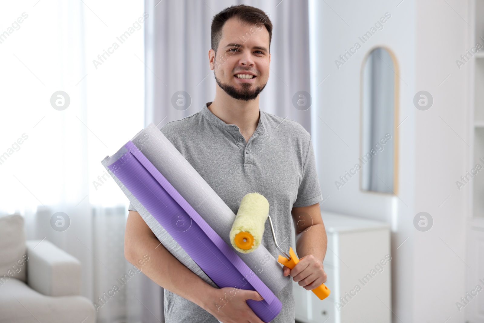 Photo of Man with wallpaper rolls and roller in room